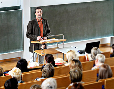 Dozent der Sexualpädagogik referiert während einer Fachtagung im Hörsaal vor einem großen Publikum