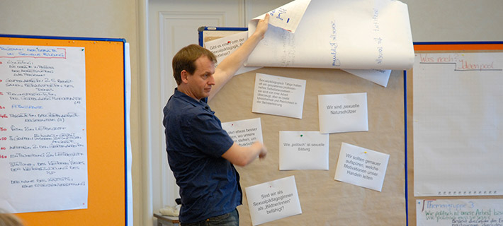 Dozent steht während eines Seminars am Board mit Beitragszetteln.