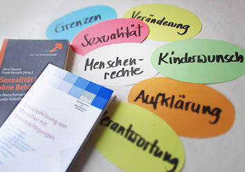 Bücher und Begriffe auf Zetteln zum Thema Behinderung und Sexualität.